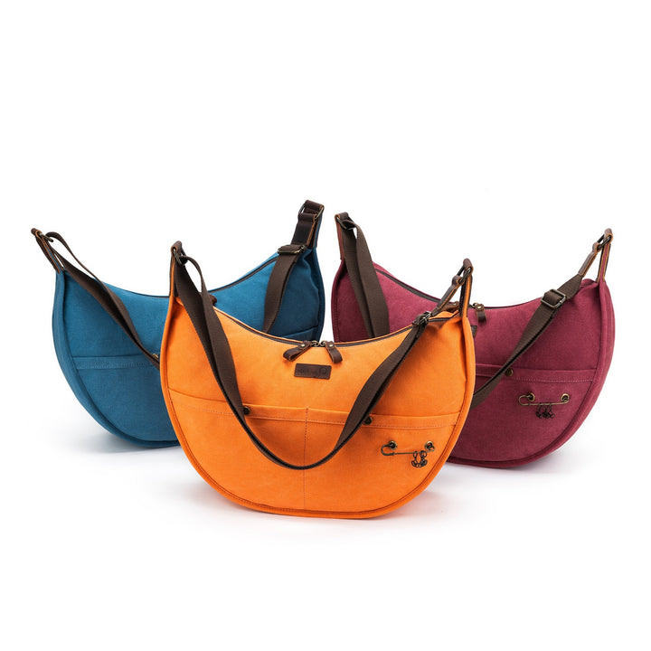 Three colorful bags (blue, orange, red) with brown straps on a white background