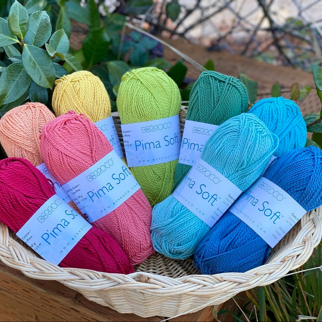 A basket filled with skeins of Pima Soft cotton yarn in various colors.