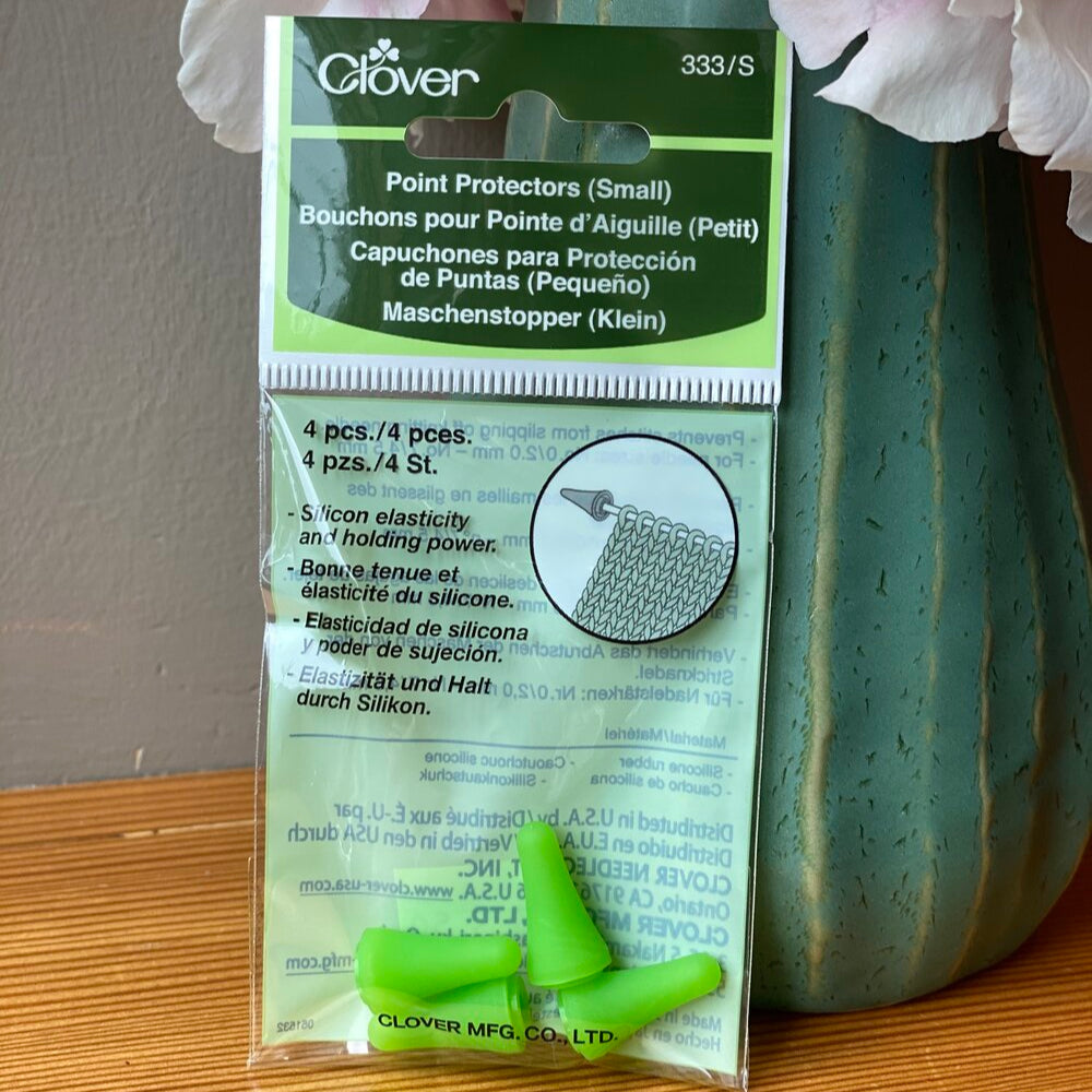 Packaging of Clover point protectors, containing 4 pieces, displayed in front of a floral background.