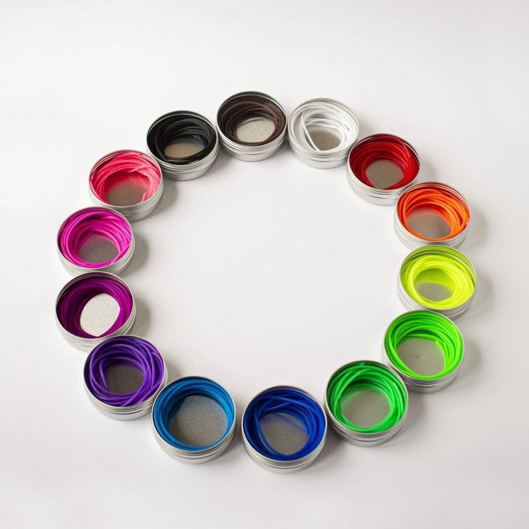 A collection of colorful circular stitch holders in various sizes, displayed in a spiral pattern on a white background, with a metal case lid at the top.