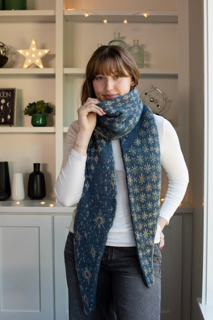 A person wearing a navy-colored shawl with a star pattern.