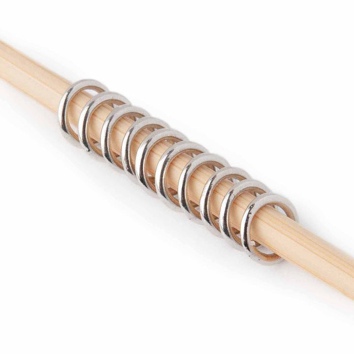 Wooden knitting needle with metal stitch markers a white background
