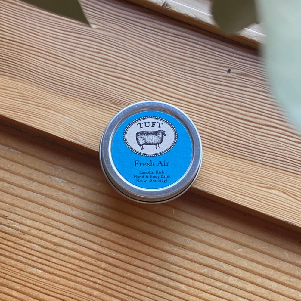 Small round container labeled 'TUFT Fresh Air' on a wooden surface