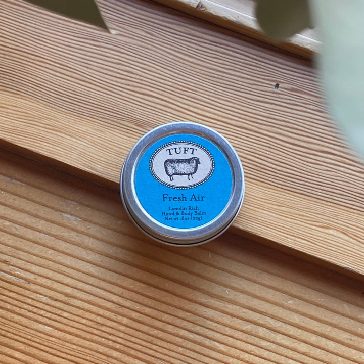 Small round container labeled 'TUFT Fresh Air' on a wooden surface