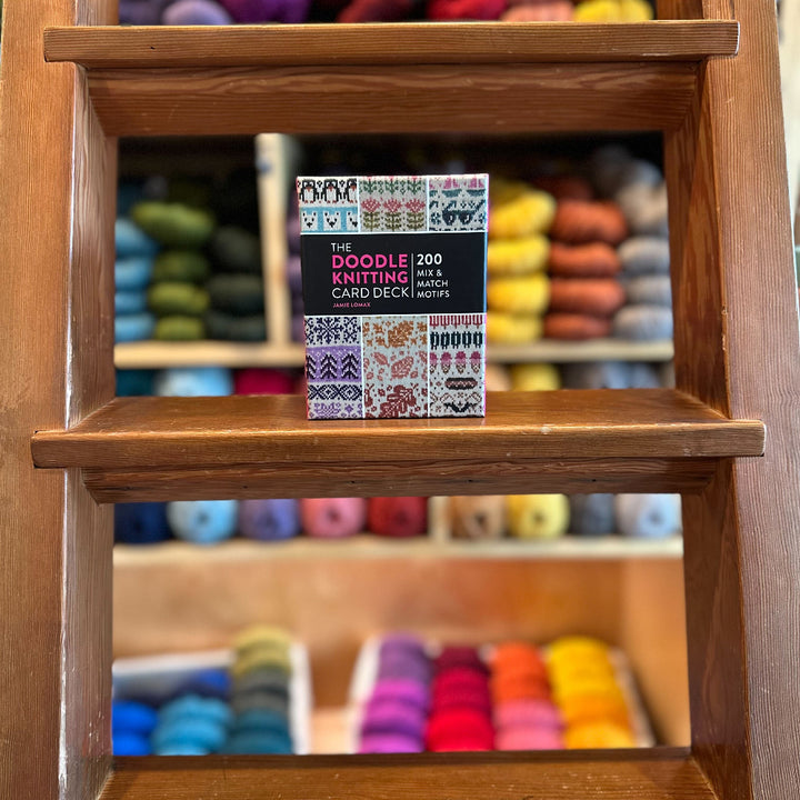 Wooden shelf with colorful yarn and a card deck on a wooden surface