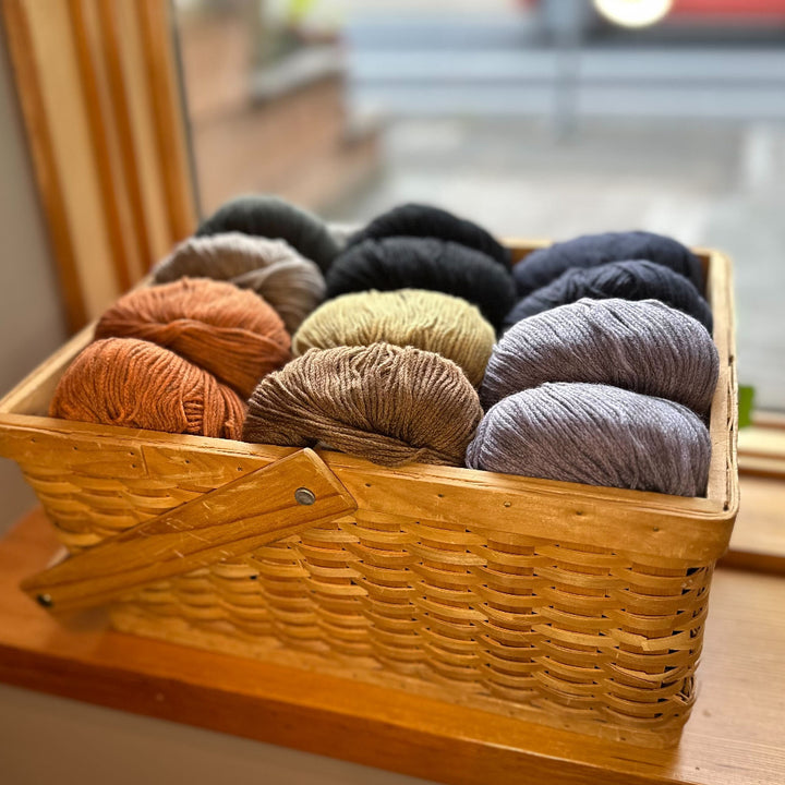 Basket of multicolored yarn on a wooden shelf