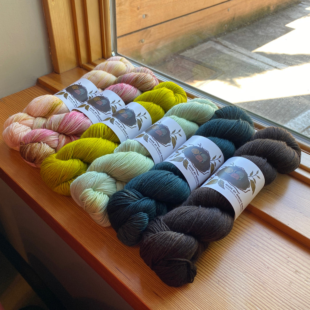 Colorful yarn skeins on a wooden surface with a window in the background
