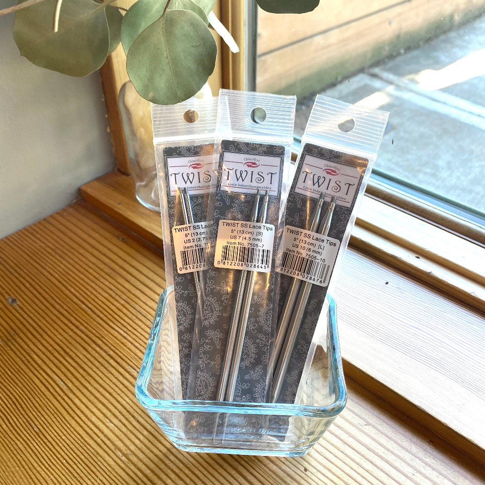 Three packages of 'Twist' brand products in a glass container on a wooden surface with a window in the background.