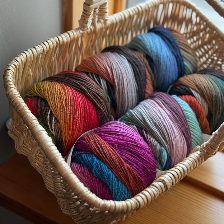 Wicker basket filled with colorful yarn on a wooden surface