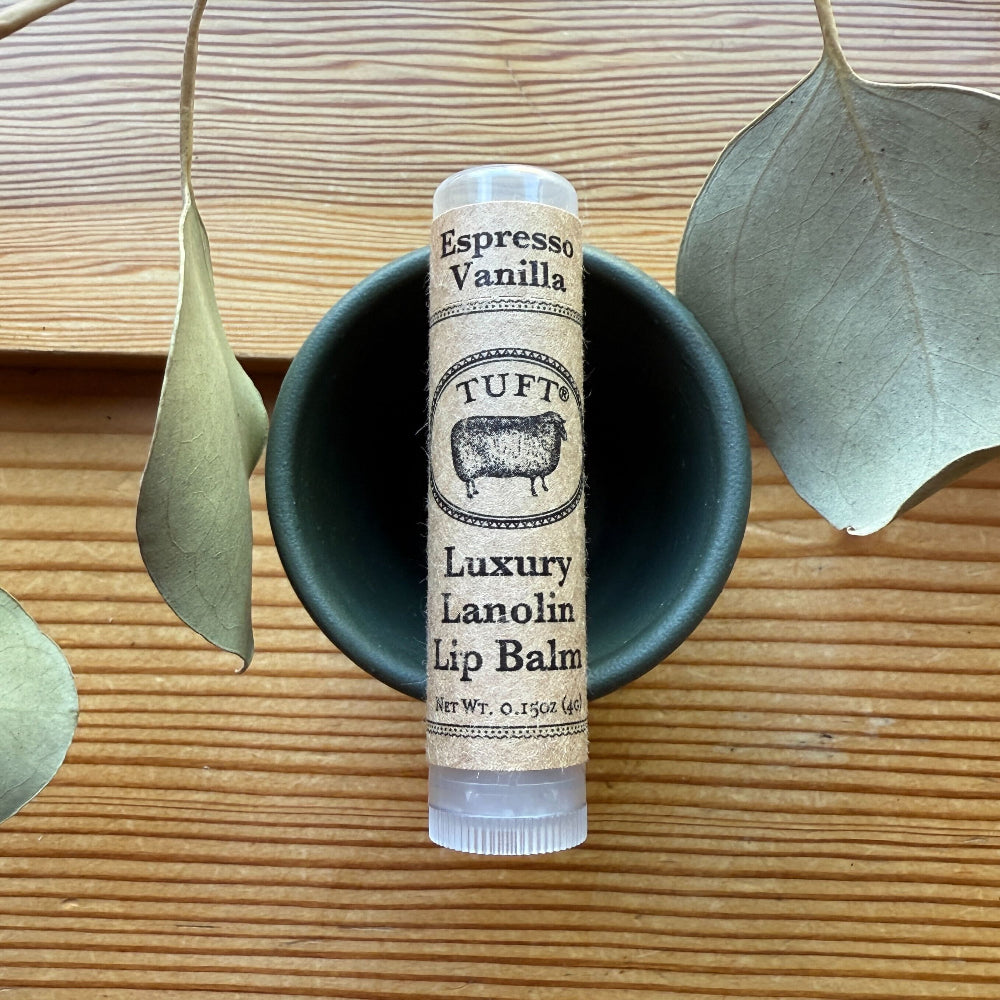 TUFTS Espresso Vanilla Luxury Lanolin Lip Balm on a wooden surface with leaves.
