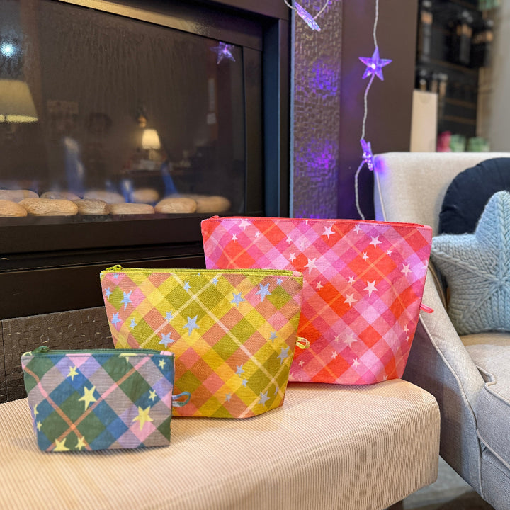 Three colorful pouches on a couch with a fireplace and decorative lights in the background