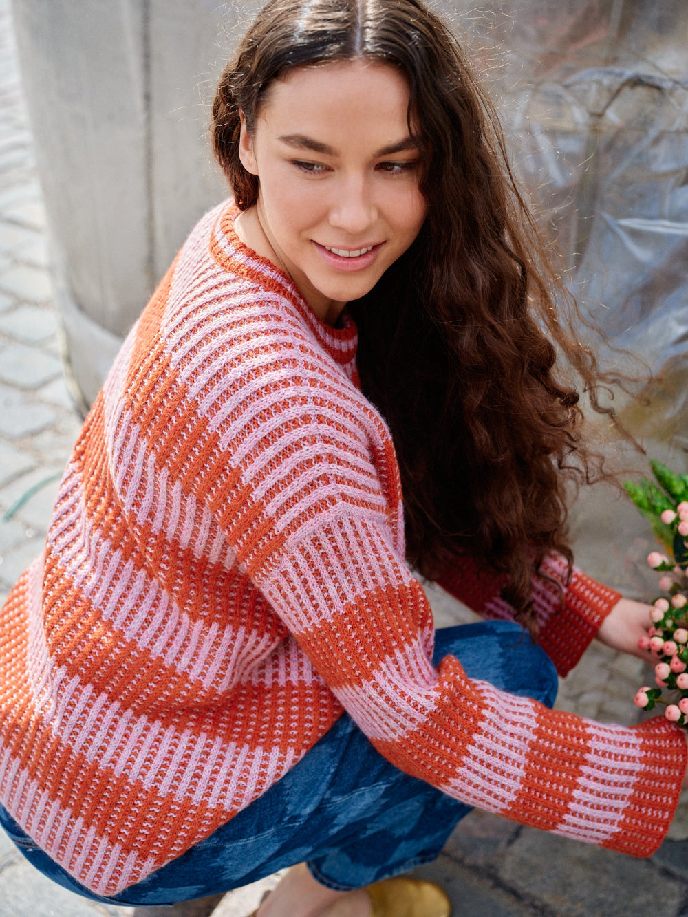 Woman wearing a red and white striped sweater sitting outdoors.