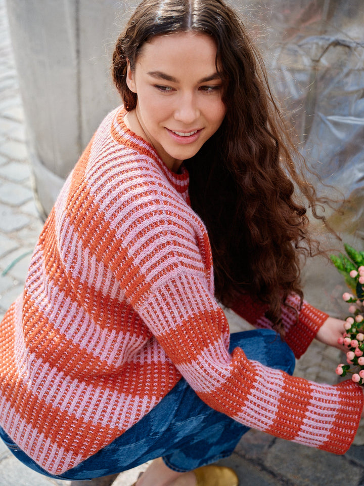 Woman wearing a red and white striped sweater sitting outdoors.