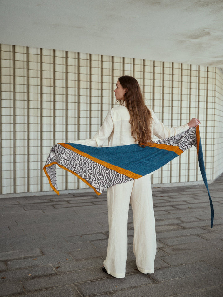 Person holding a colorful woven fabric against a neutral background