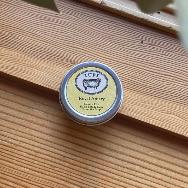 Small tin labeled 'Royal Apiary' by 'TUFT' on a wooden surface