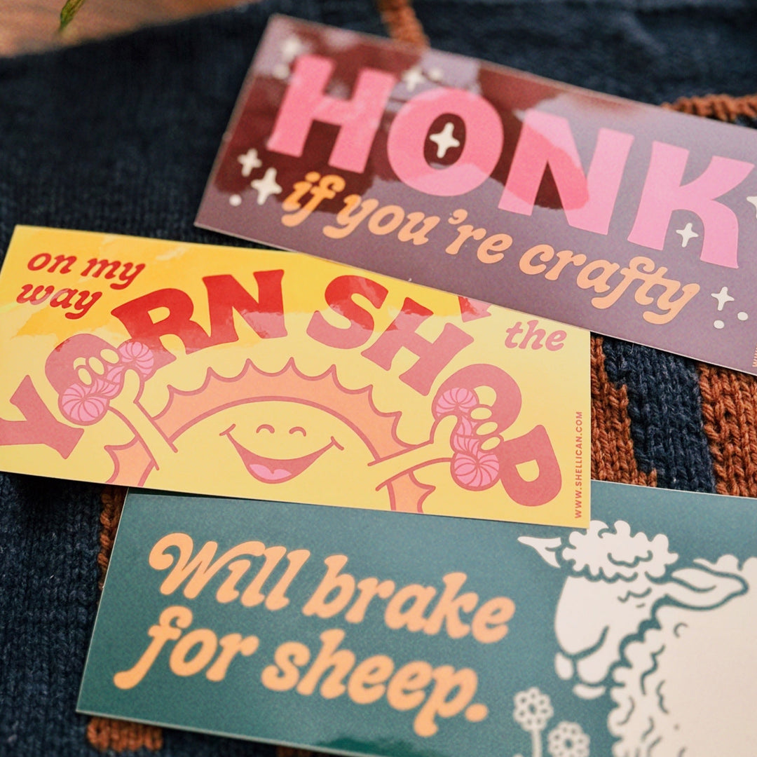 Four colorful bumper stickers on a denim background