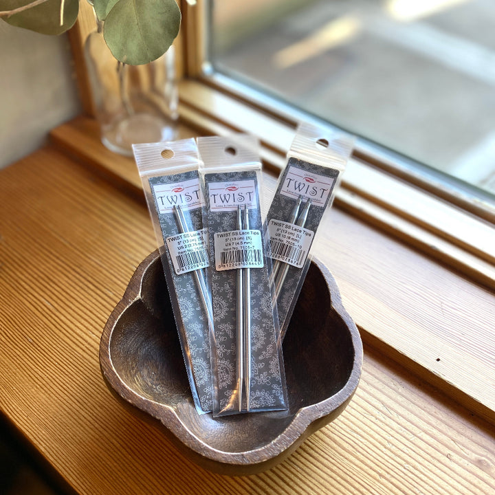 Three packages of 'TWIST' products on a wooden surface with a window in the background.