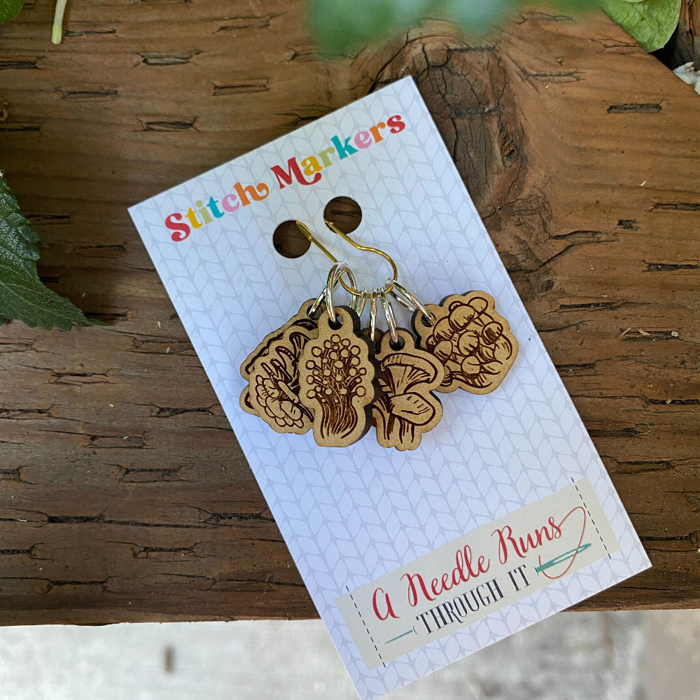 Set of wooden stitch markers on a branded card with nature-themed design.