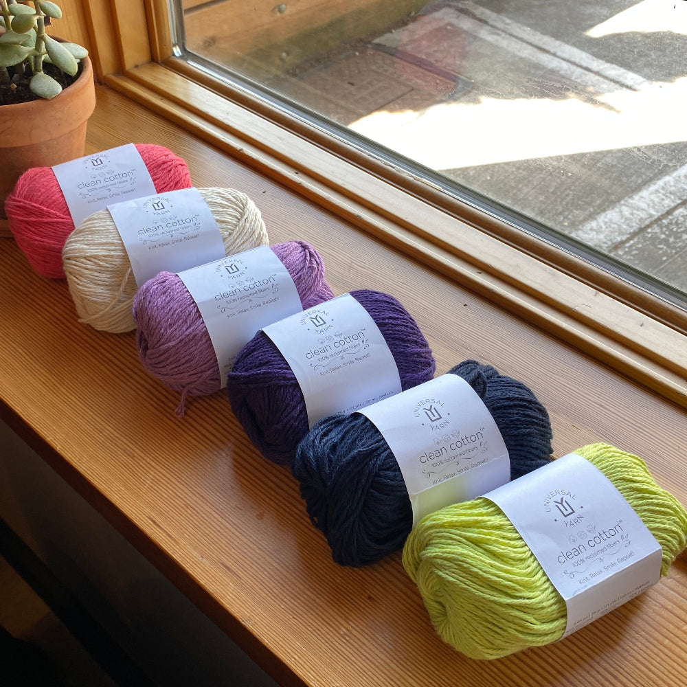 Five skeins of clean cotton yarn in various colors on a windowsill
