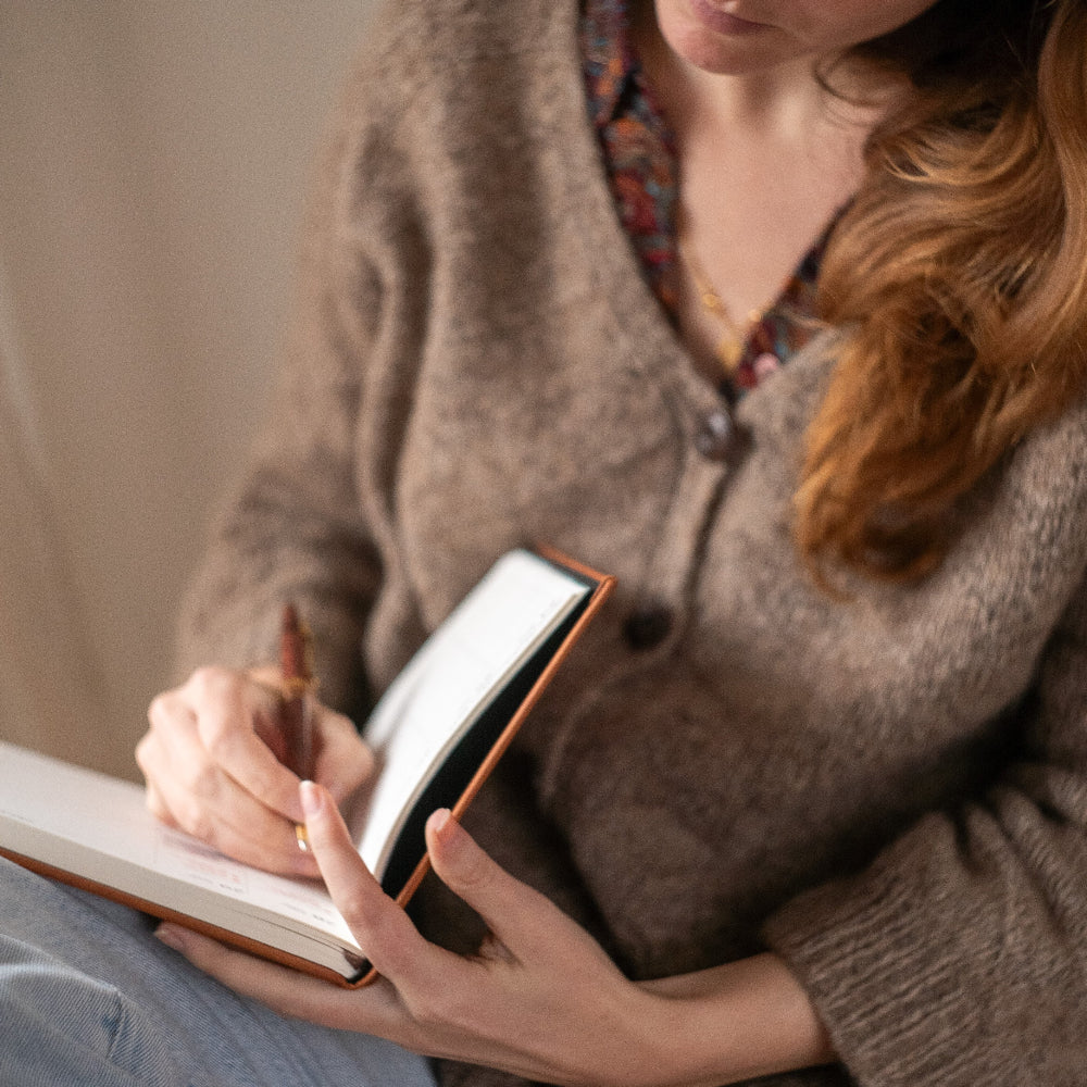 Woman writing in a notebook with a warm, cozy atmosphere