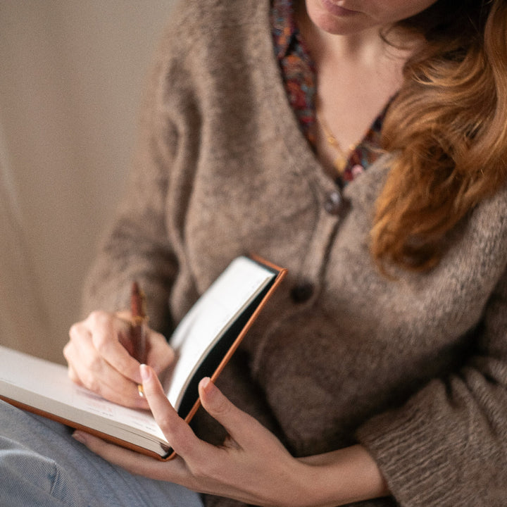 Woman writing in a notebook with a warm, cozy atmosphere